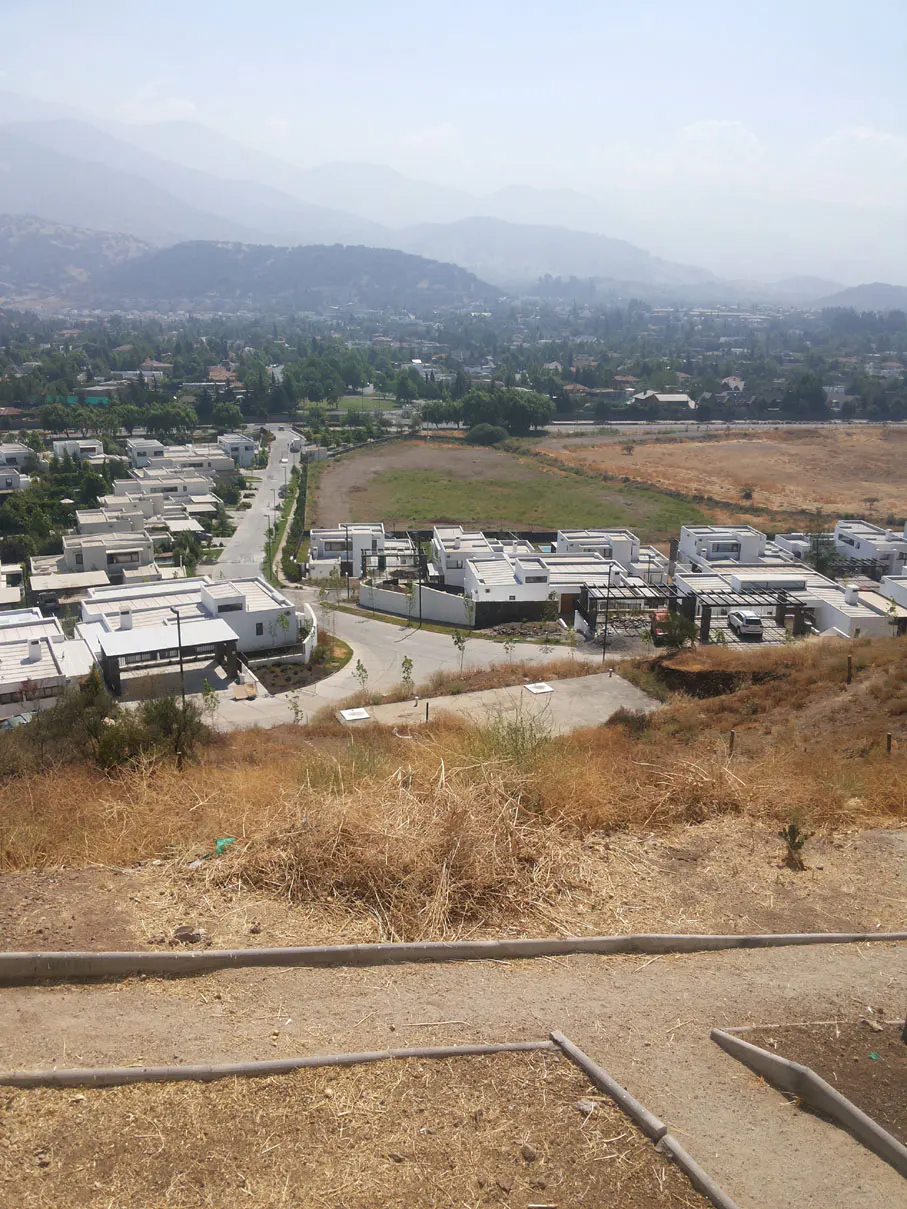 A high-angle view of modern white houses in a valley, with mountains in the background.