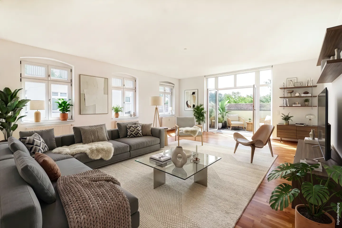 Bright living room with gray sectional sofa, glass coffee table, and open doors to a patio with outdoor furniture.
