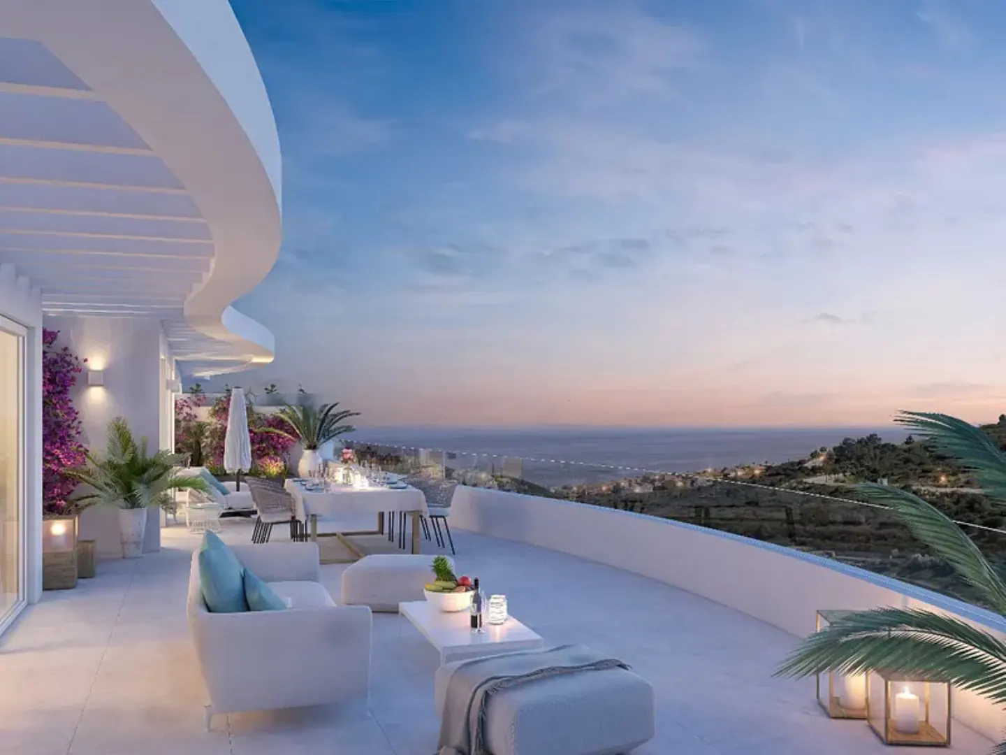Modern white terrace at sunset with outdoor seating, dining area, and panoramic ocean views.