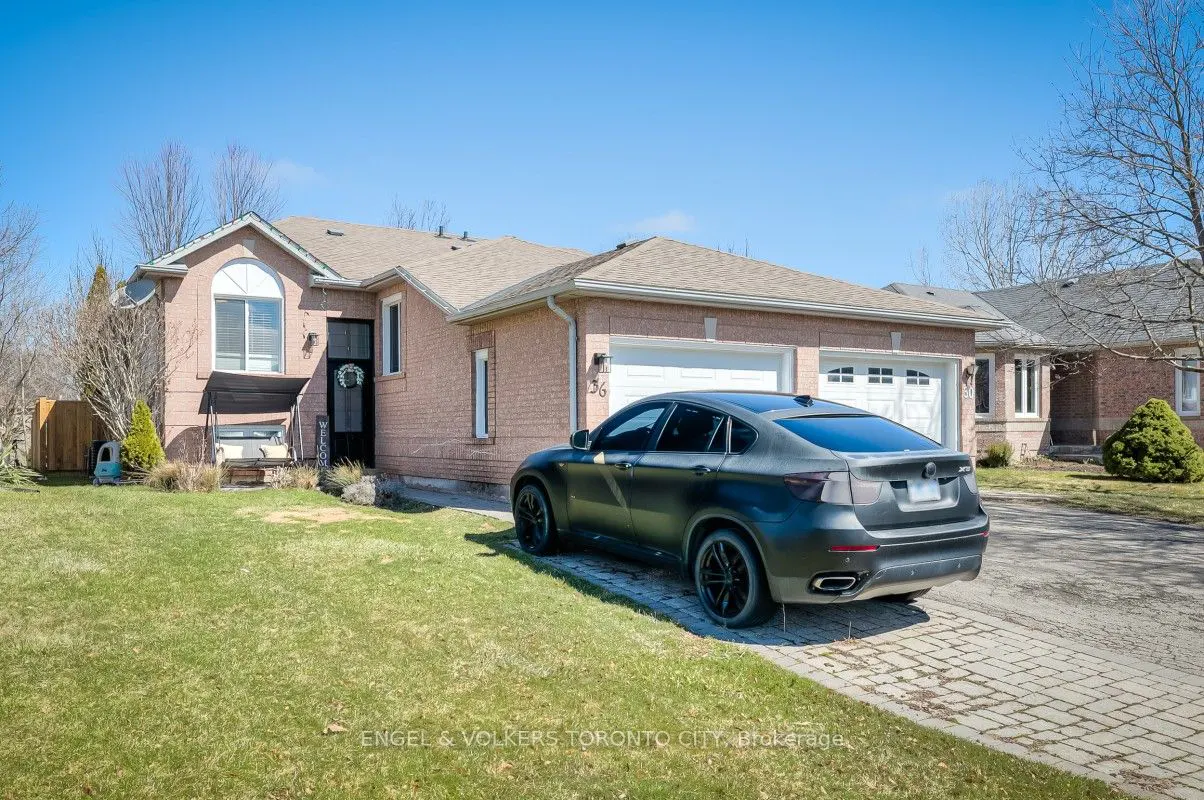 A one-story brick house with a gray car parked in the driveway on a sunny day.