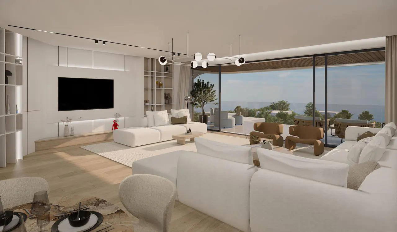 Modern living room with white sofas, brown accent chairs, and large glass doors opening to a scenic ocean view.