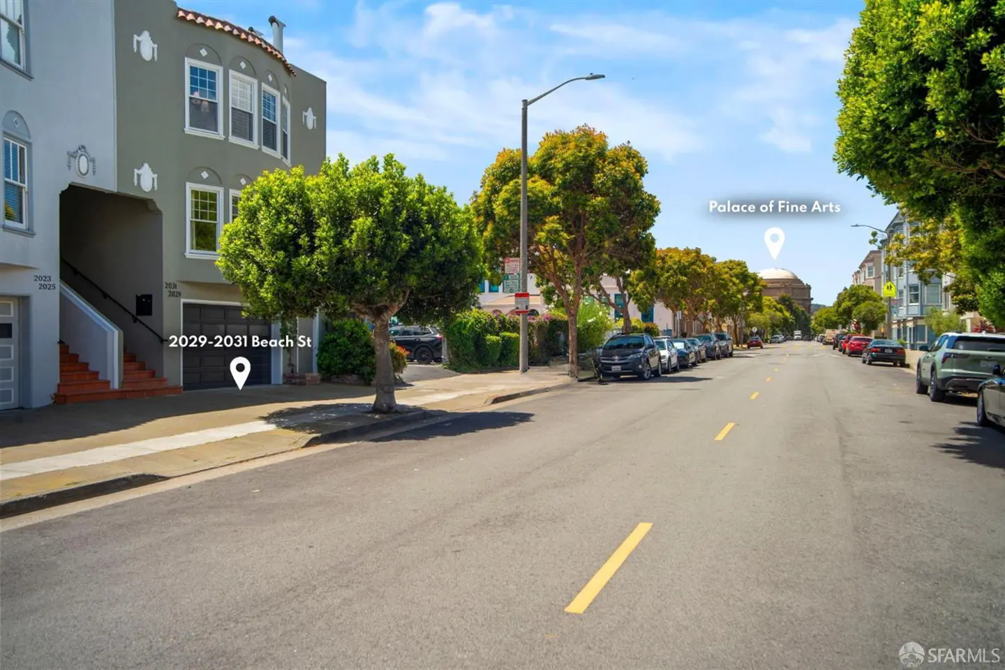 Street view of gray townhouses on Beach Street in San Francisco, with the Palace of Fine Arts visible in the distance. Cars are parked along the street.