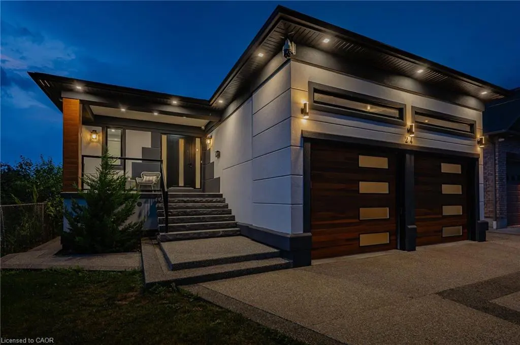 Exterior shot of a modern, two-story home at dusk with a two-car garage, stone steps, and a small porch with a chair.
