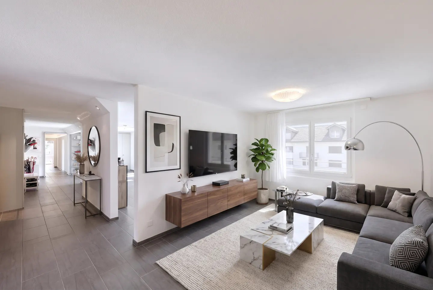 Modern living room with a grey sectional sofa, marble coffee table, wall-mounted wood media console, and a view of a hallway.
