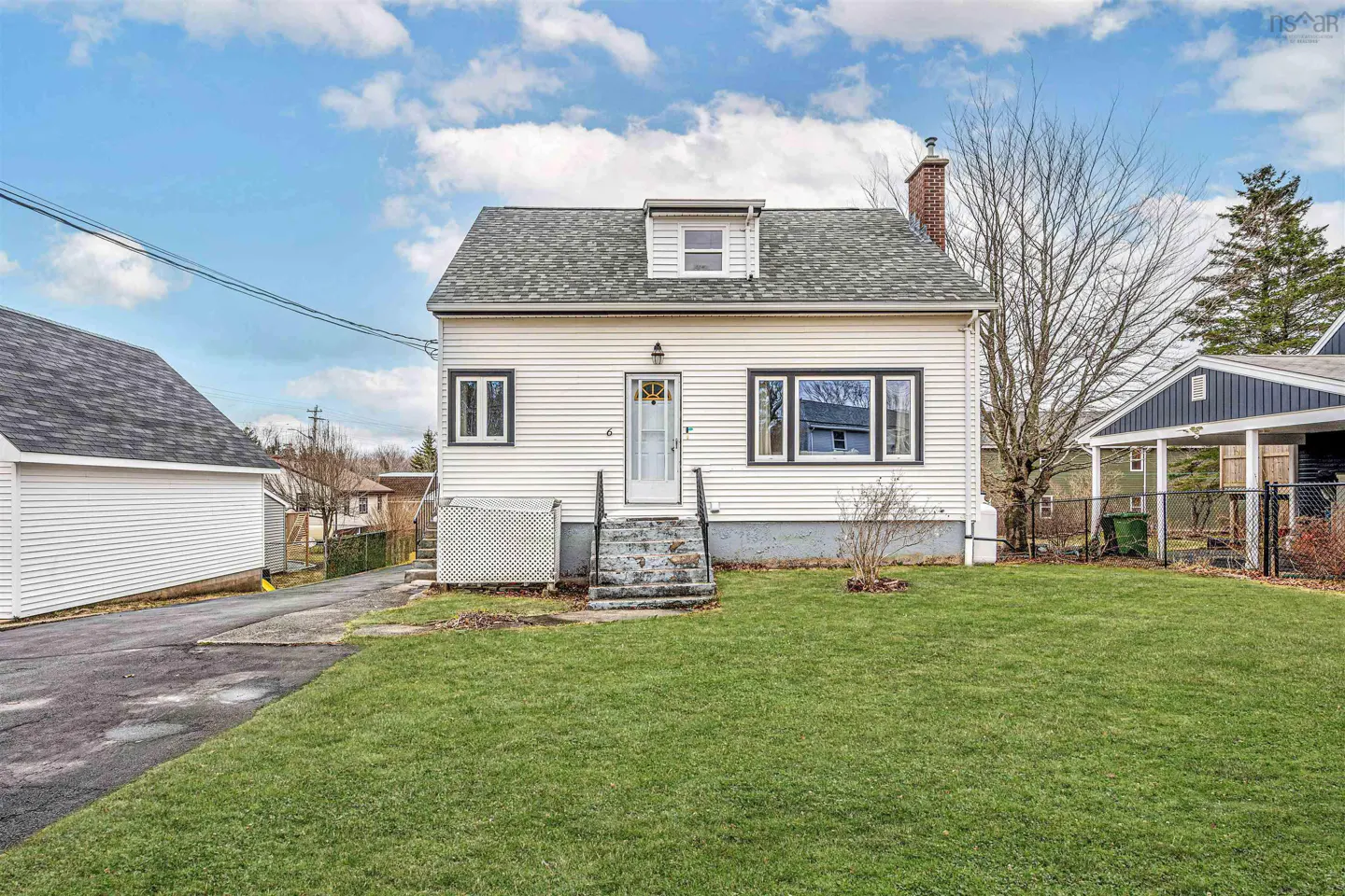 Exterior of a white, two-story house with a gray roof and green lawn under a blue sky with clouds.