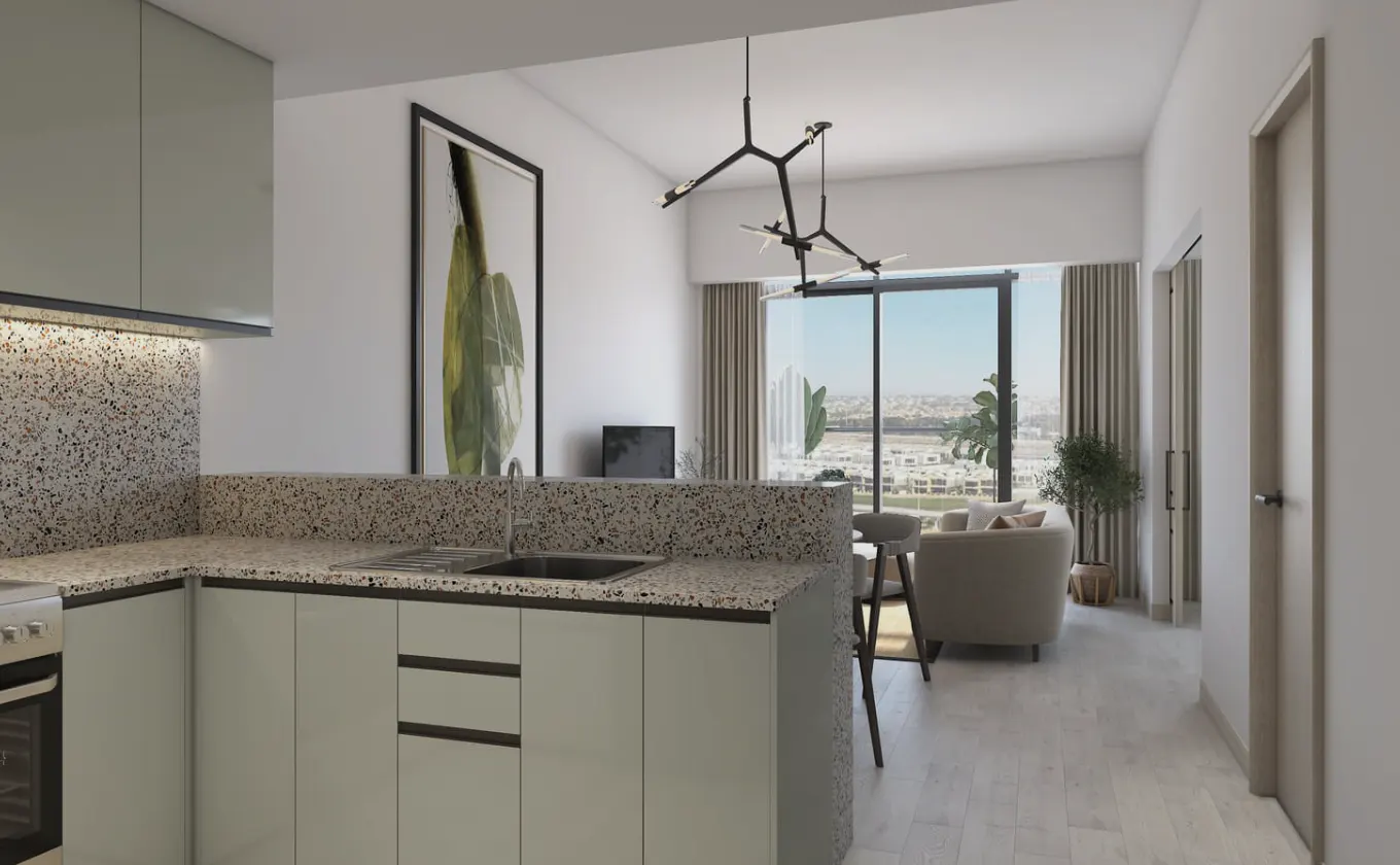 A modern apartment interior featuring a kitchen with light green cabinets and speckled countertops, opening to a living area with a large window view.