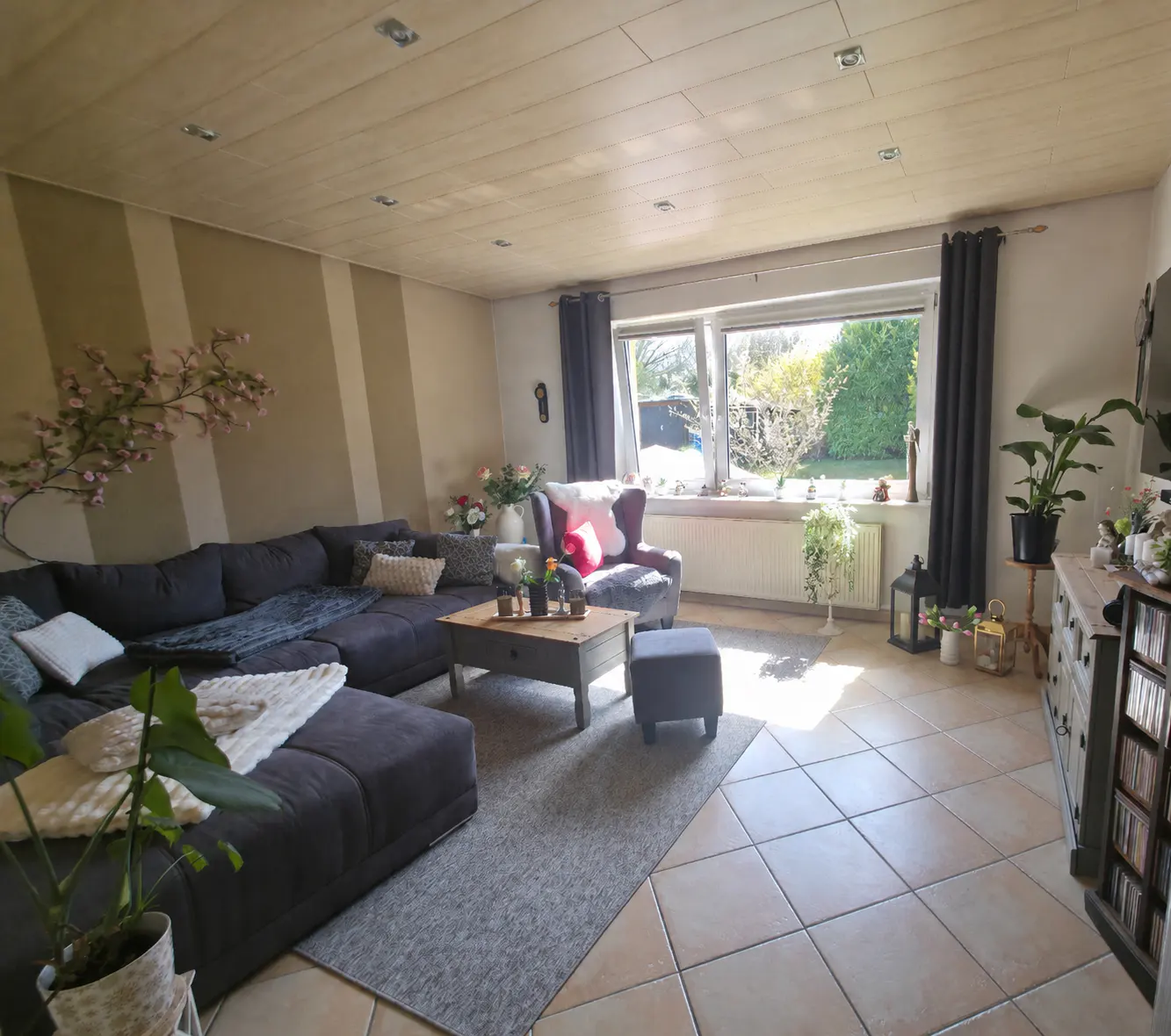 Living room with a large gray sectional sofa, a gray armchair, and a gray rug. A large window looks out onto a green yard.