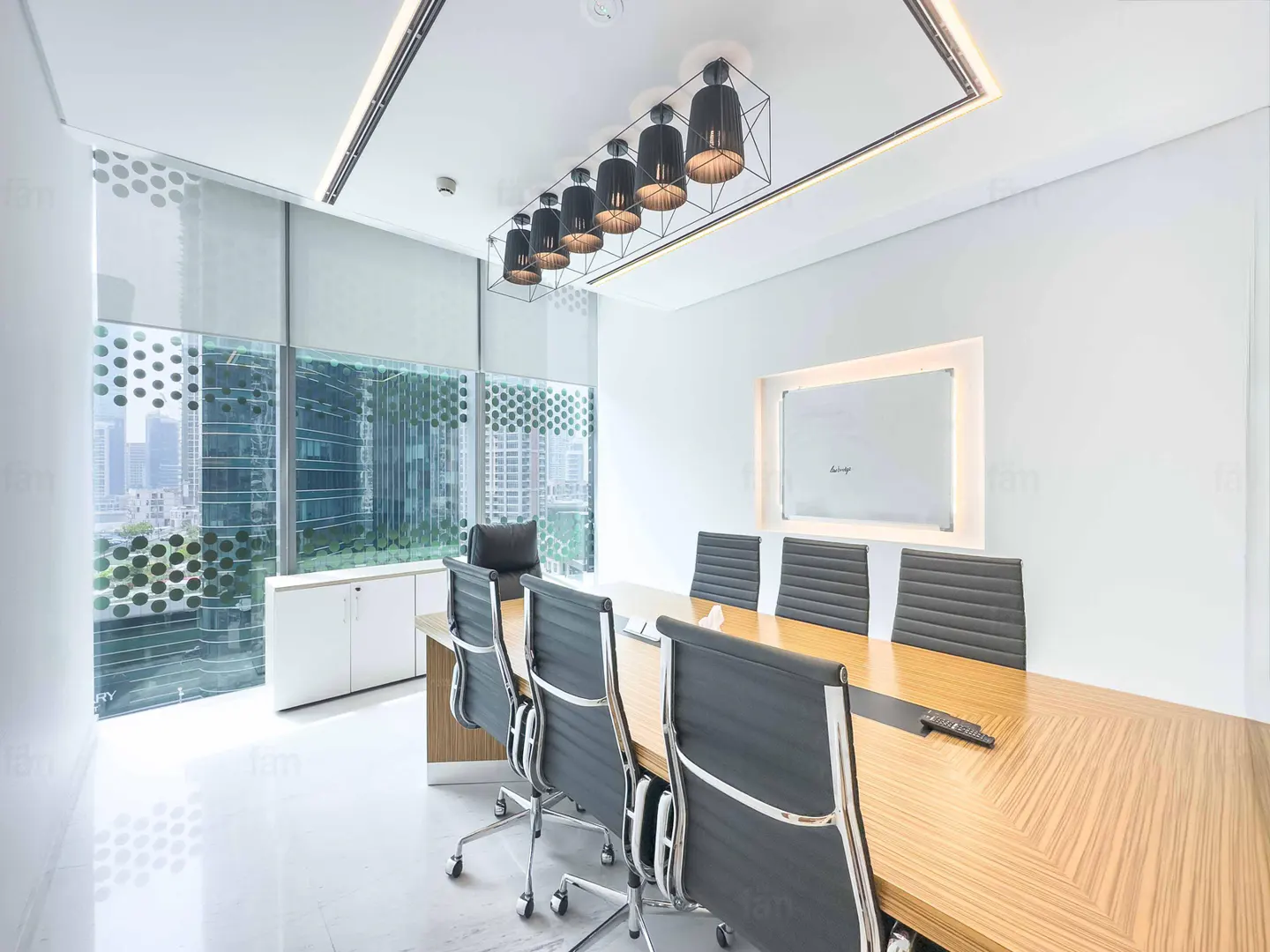 Bright, modern conference room with a long wood table, black chairs, and a whiteboard. Large windows offer a city view.