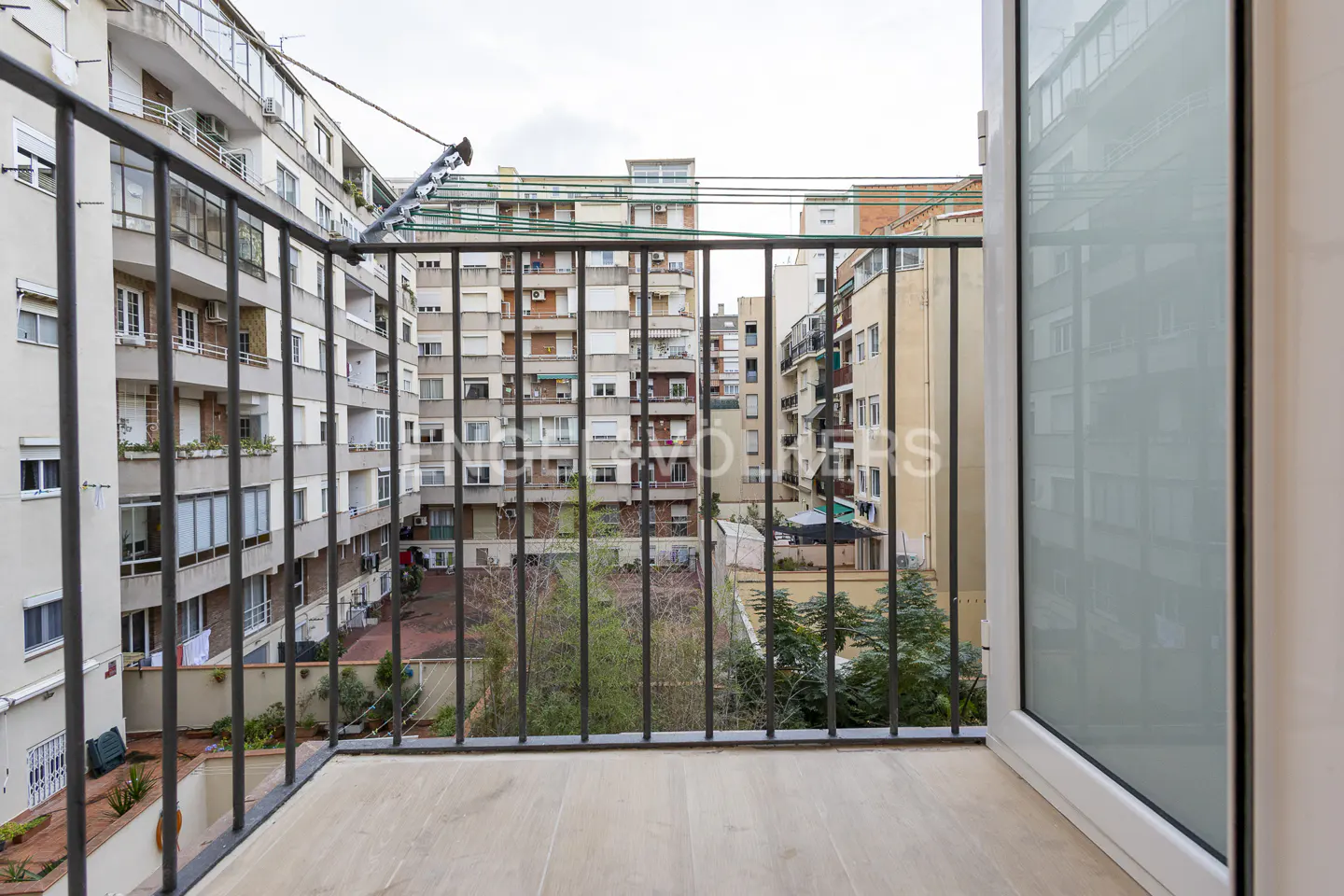 View from a balcony with black metal railings overlooking a courtyard and apartment buildings.