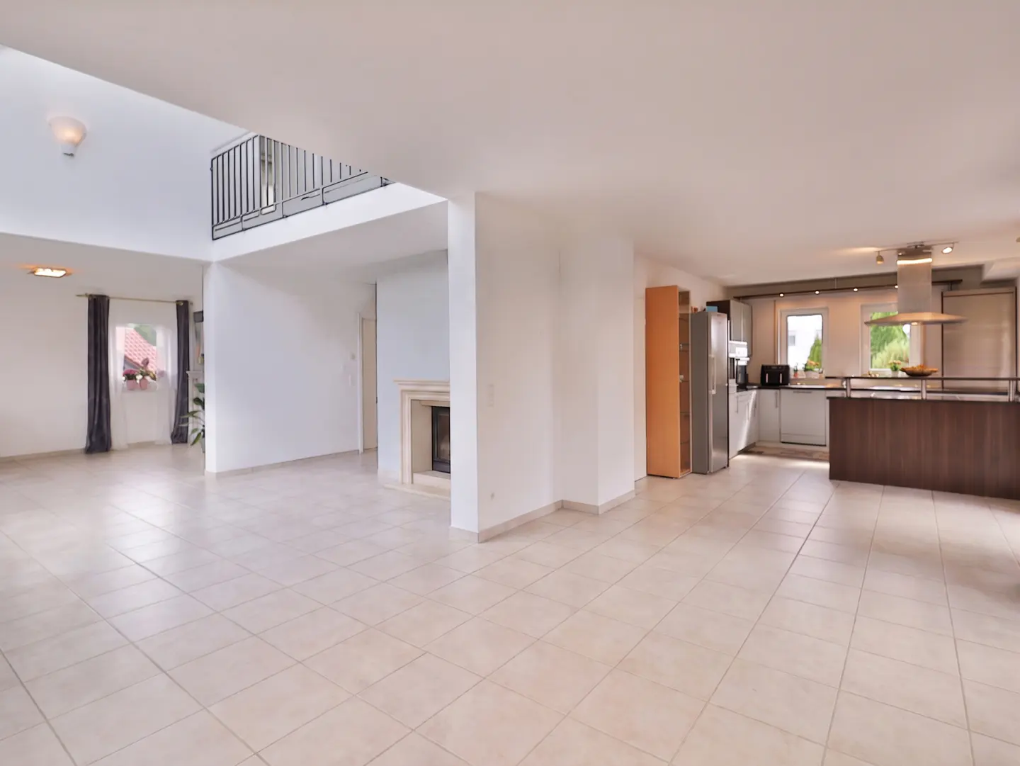Open-concept living space with tile flooring, white walls, and a modern kitchen with stainless steel appliances.