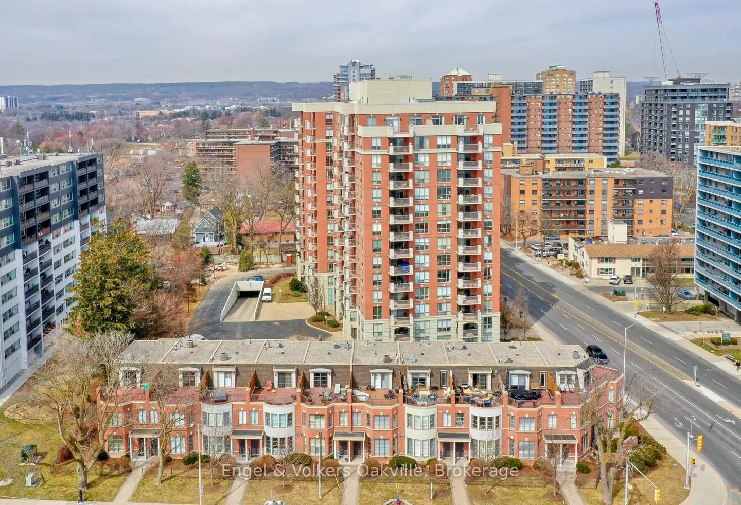 Aerial view of red brick townhouses and a high-rise apartment building in an urban setting.