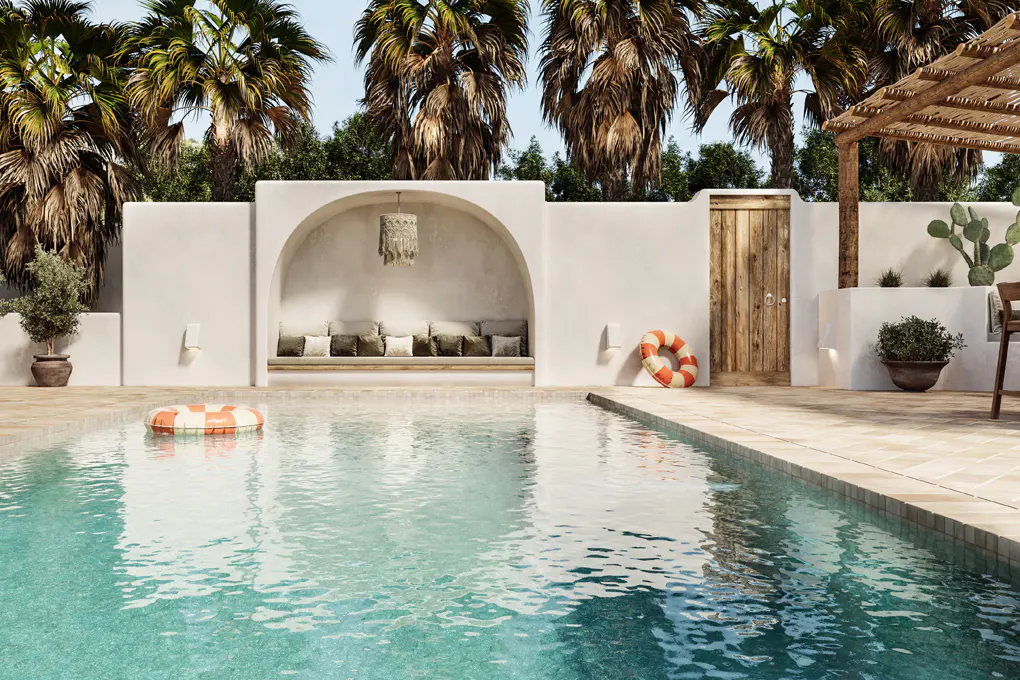 A turquoise pool with a striped floatie, surrounded by a white wall with an arched alcove, a wooden door, and palm trees.