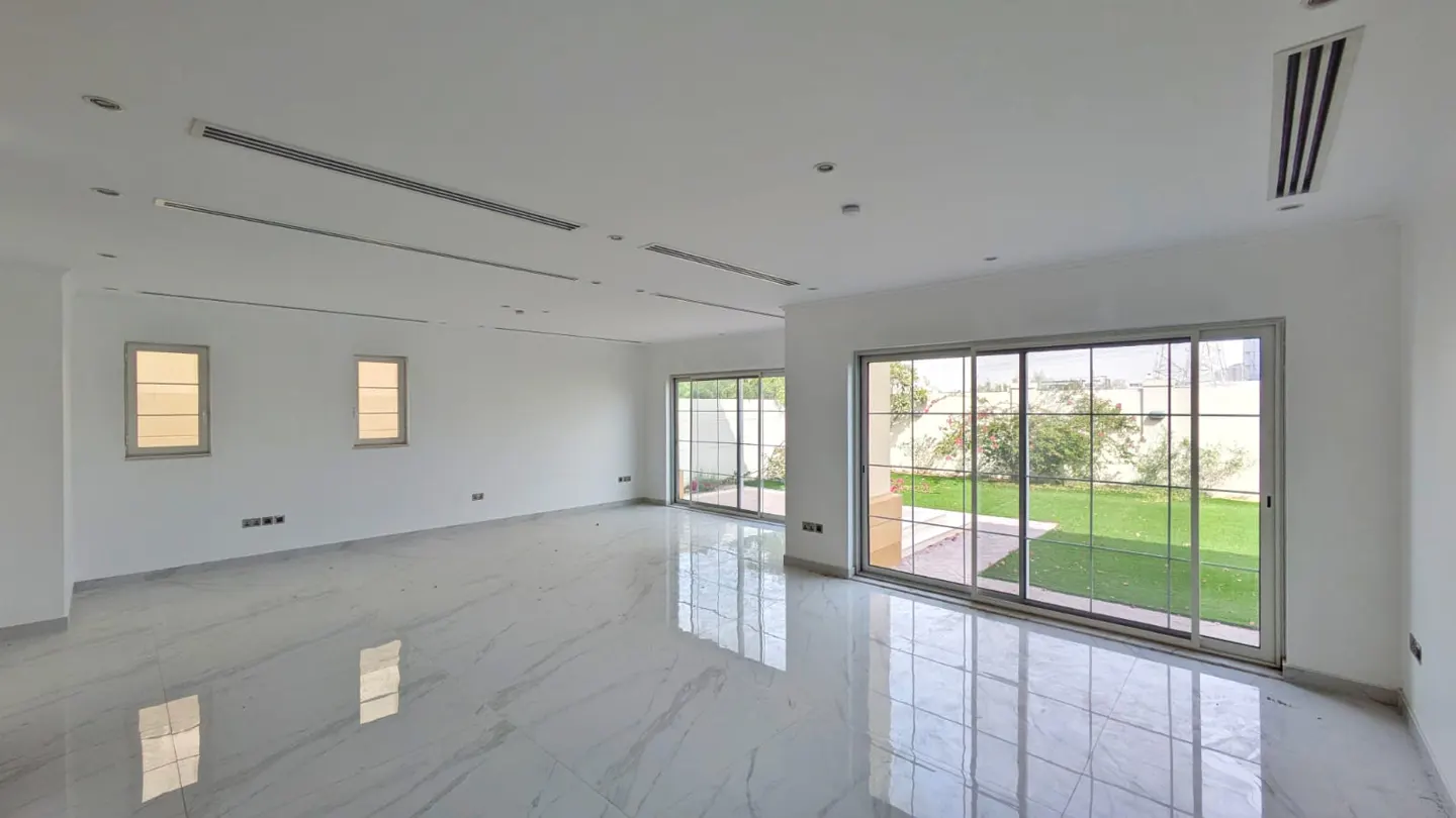 Bright, empty room with white walls, marble floors, and large sliding glass doors to a green lawn.