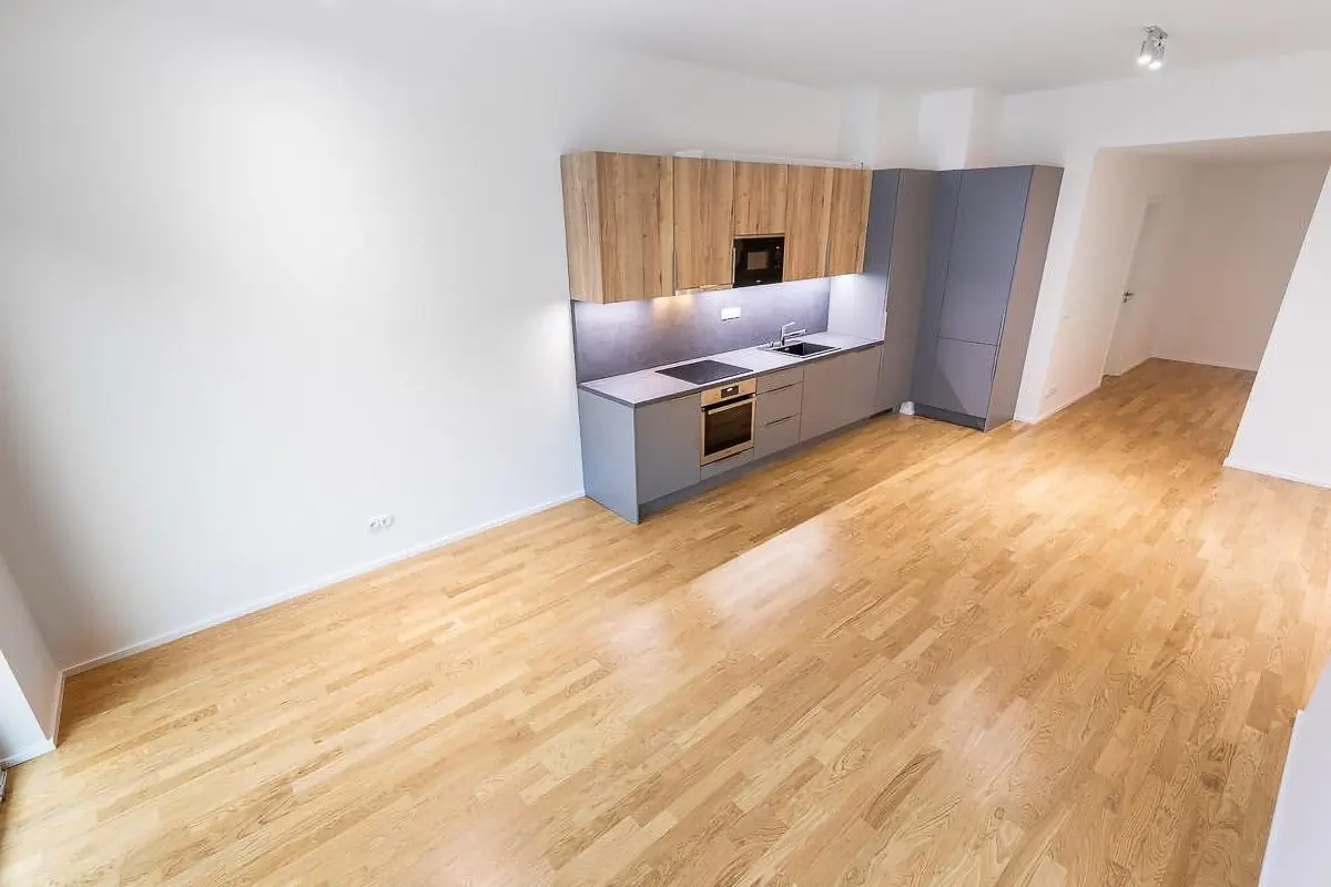 Bright, modern apartment with light wood floors and a gray and wood kitchen.