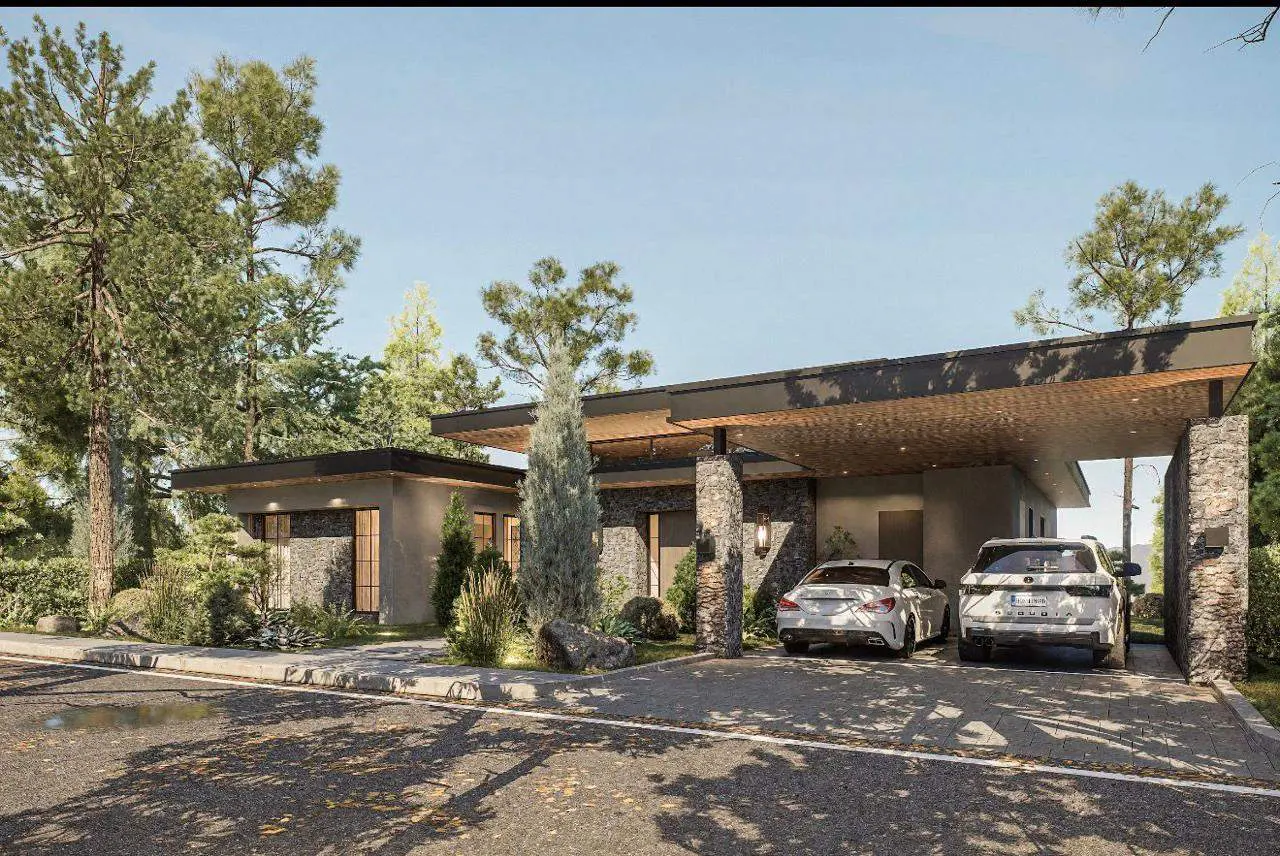 Modern stone house with a flat roof and carport. Two cars are parked in the driveway, surrounded by trees.