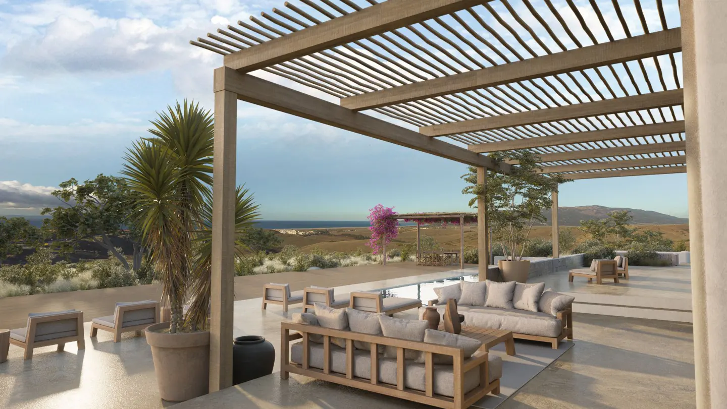 Outdoor patio with wooden pergola, sofas, chairs, and potted plants overlooking a landscape with ocean view.