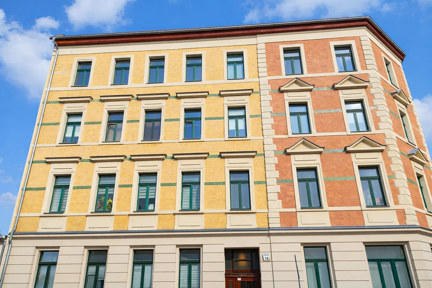 A low-angle shot of a yellow and orange brick apartment building under a blue sky.