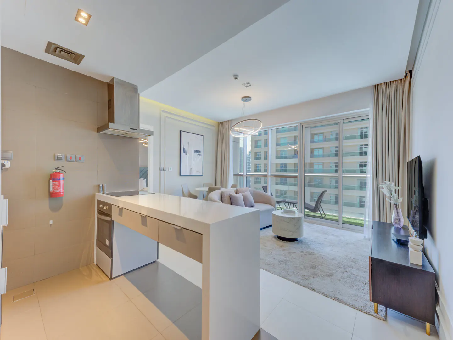 A modern apartment interior with a kitchen island, living area, and balcony with city views.