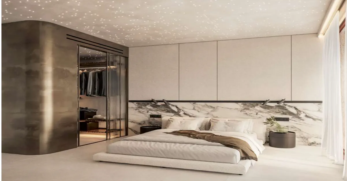 Modern bedroom with a white bed, marble headboard, and a closet with glass doors. The ceiling has star-like lights.