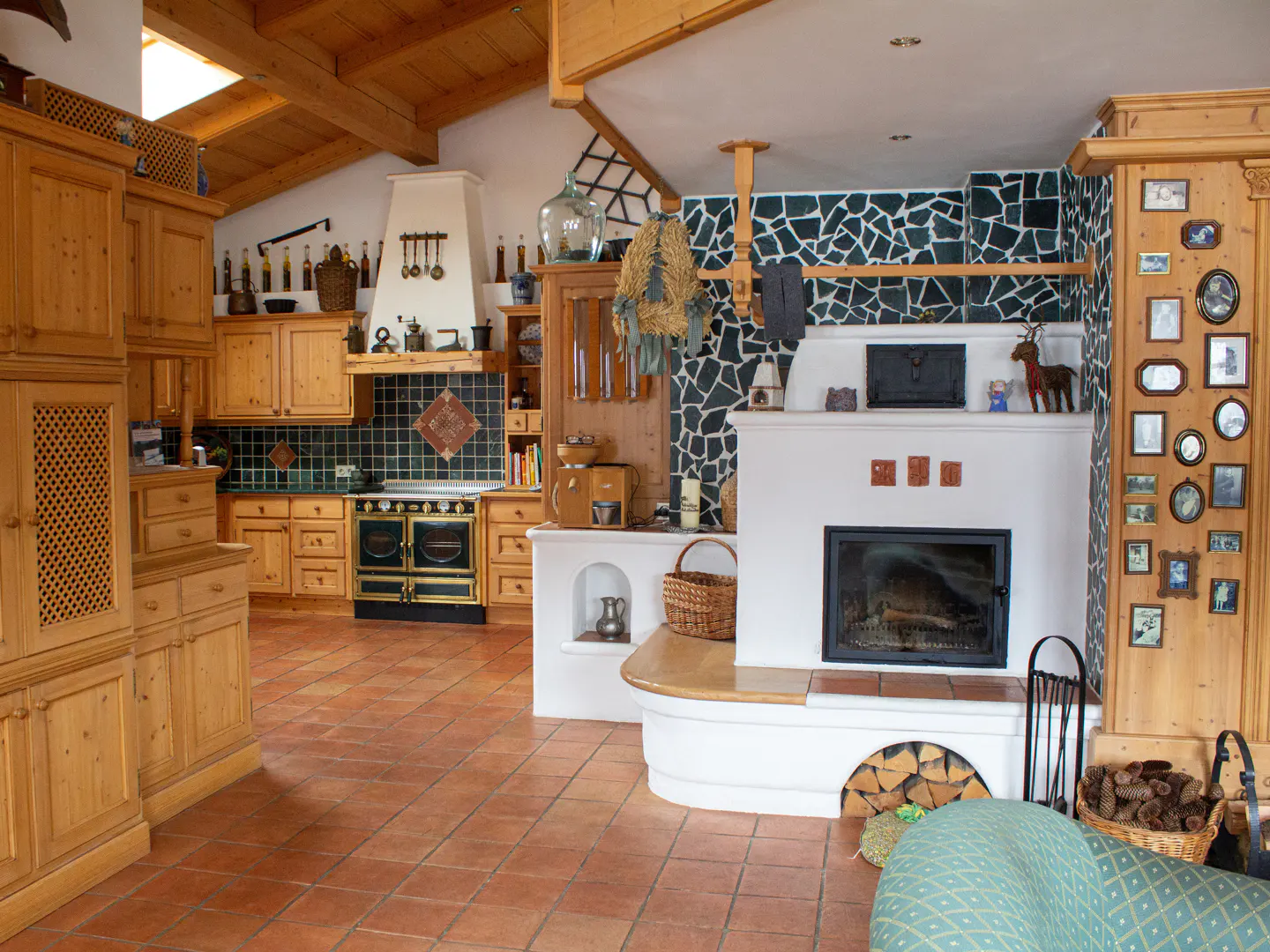 Rustic kitchen with wooden cabinets, terracotta tile floors, a white fireplace, and a black-and-gold vintage-style stove.