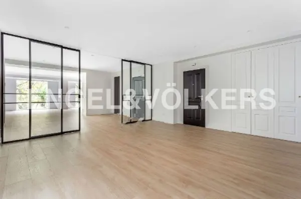Bright, empty room with light wood floors, white walls, and black framed glass doors.