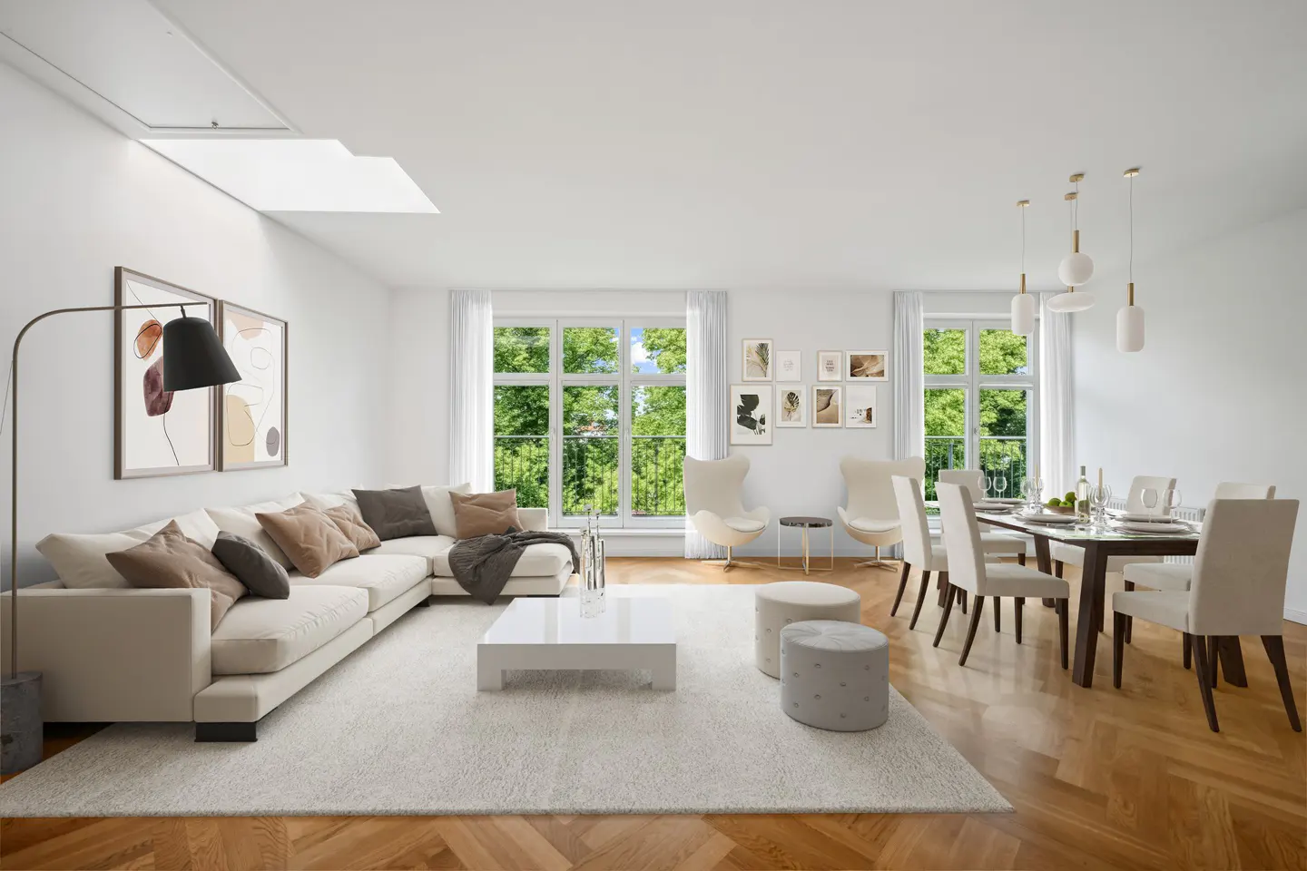 Bright, open-concept living and dining area with white walls, wood floors, and large windows overlooking greenery. A sectional sofa and dining table are featured.