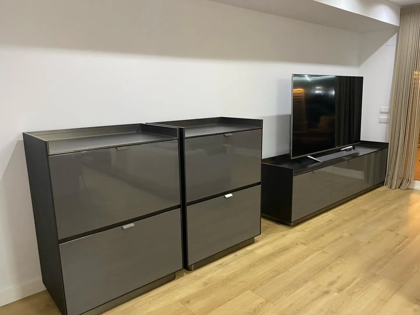 Living room with two gray cabinets, a TV on a gray stand, and light wood floors.