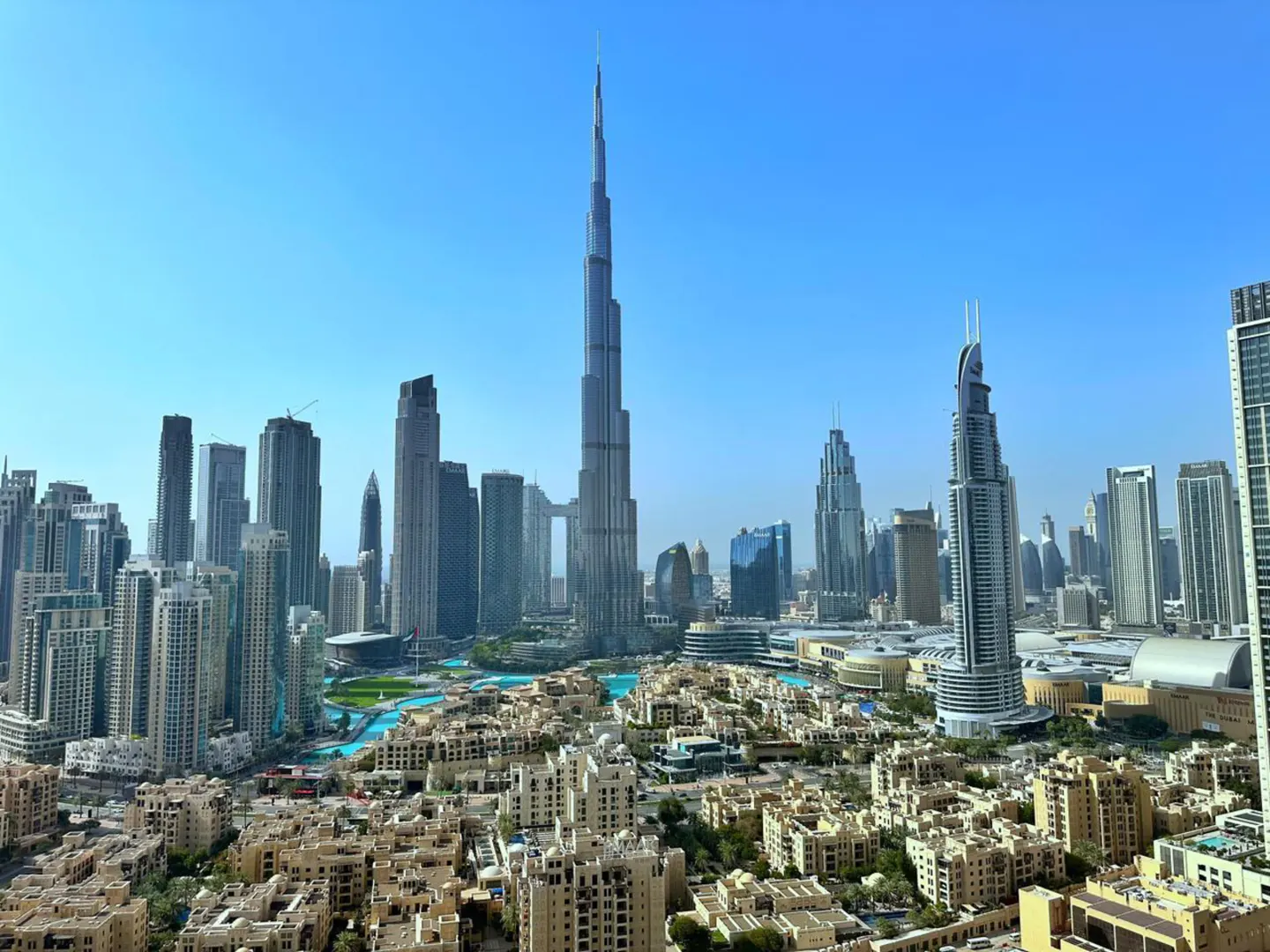 Dubai skyline view featuring the Burj Khalifa, surrounded by modern buildings and blue waterways under a clear sky.