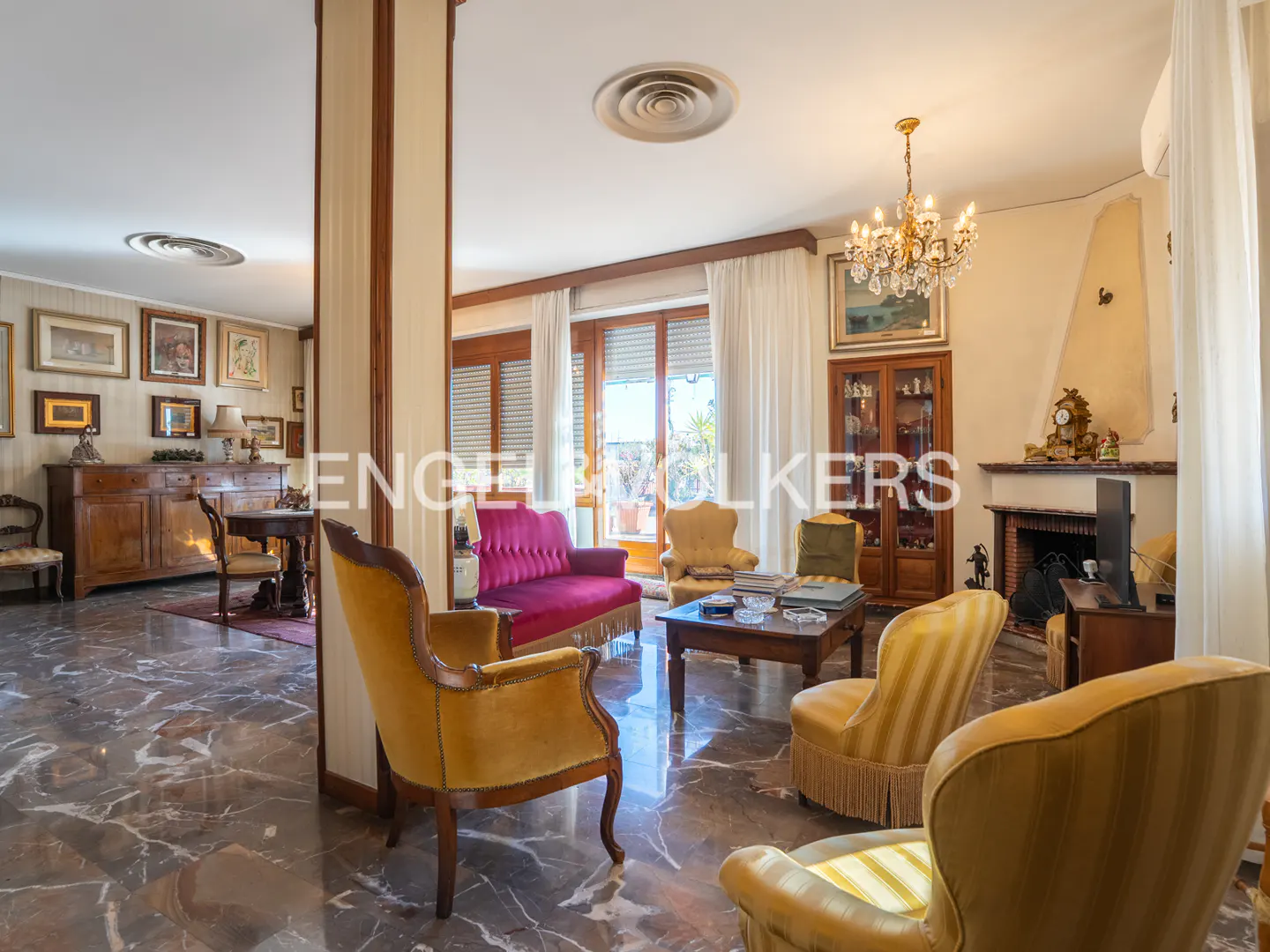 A living room with marble floors, yellow armchairs, a red sofa, and a fireplace.