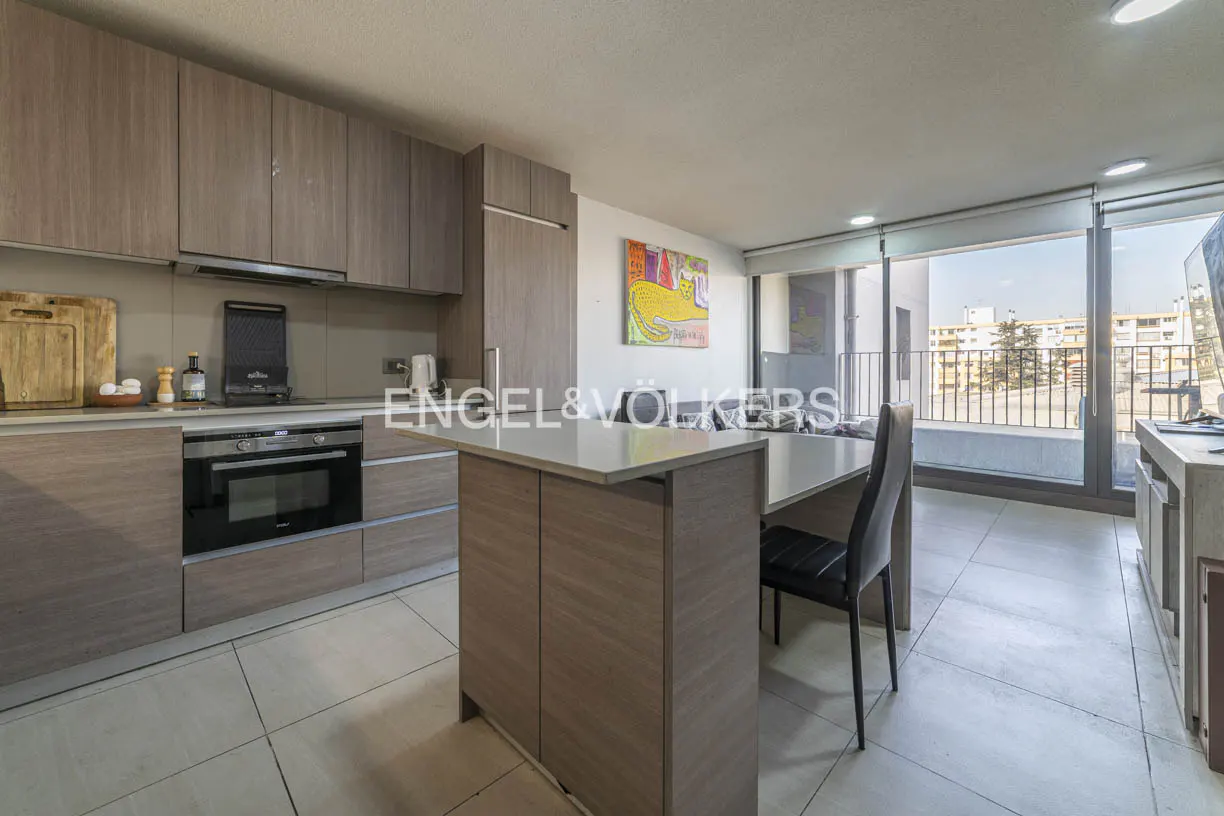 A modern kitchen with wood cabinets, a breakfast bar, and a large window with a city view.