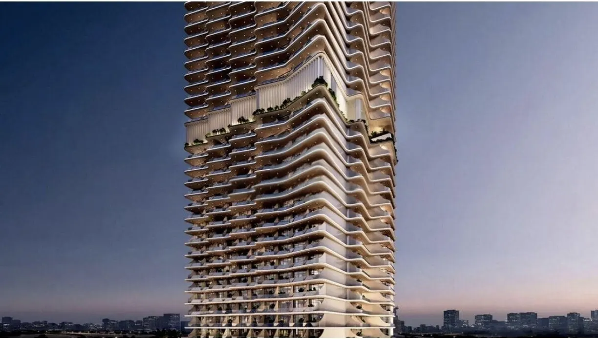 A modern high-rise building with a unique, wavy, tiered white facade against a twilight sky.