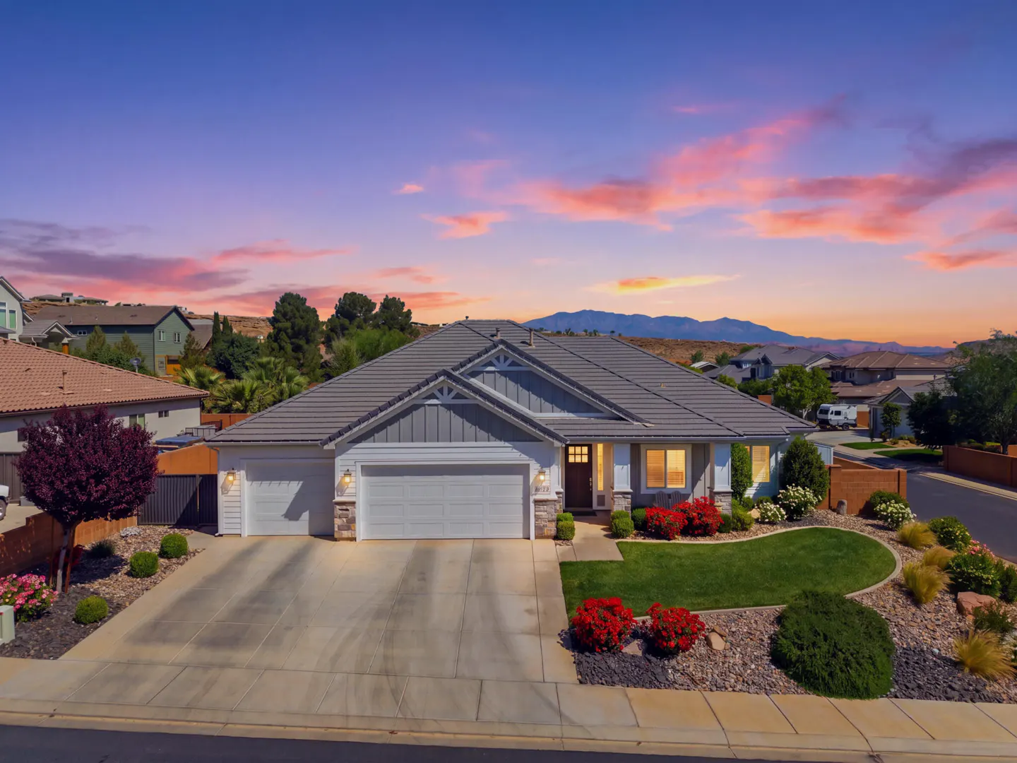 A single-story home with a gray roof, white siding, and a three-car garage at sunset.