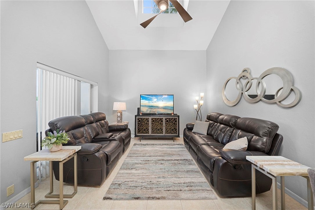 Living room with high ceilings, two dark leather sofas, a TV on a decorative console, and modern circular wall art. [AI-generated text]