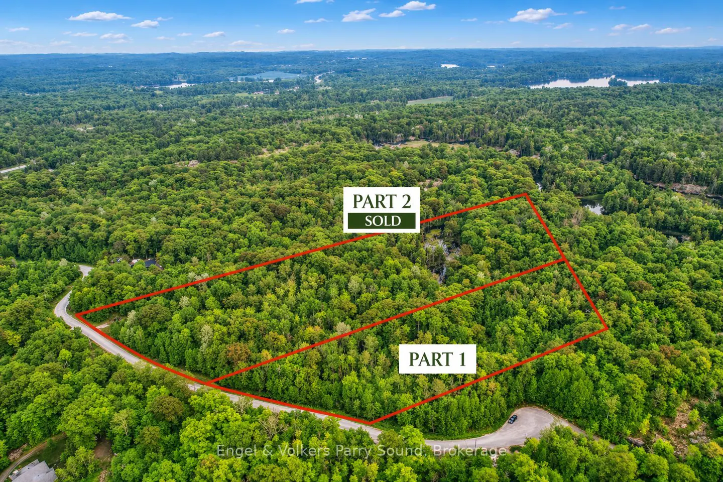 Aerial view of wooded property divided into two lots, outlined in red. "Part 2" is marked as "SOLD". Lush green trees surround the lots.