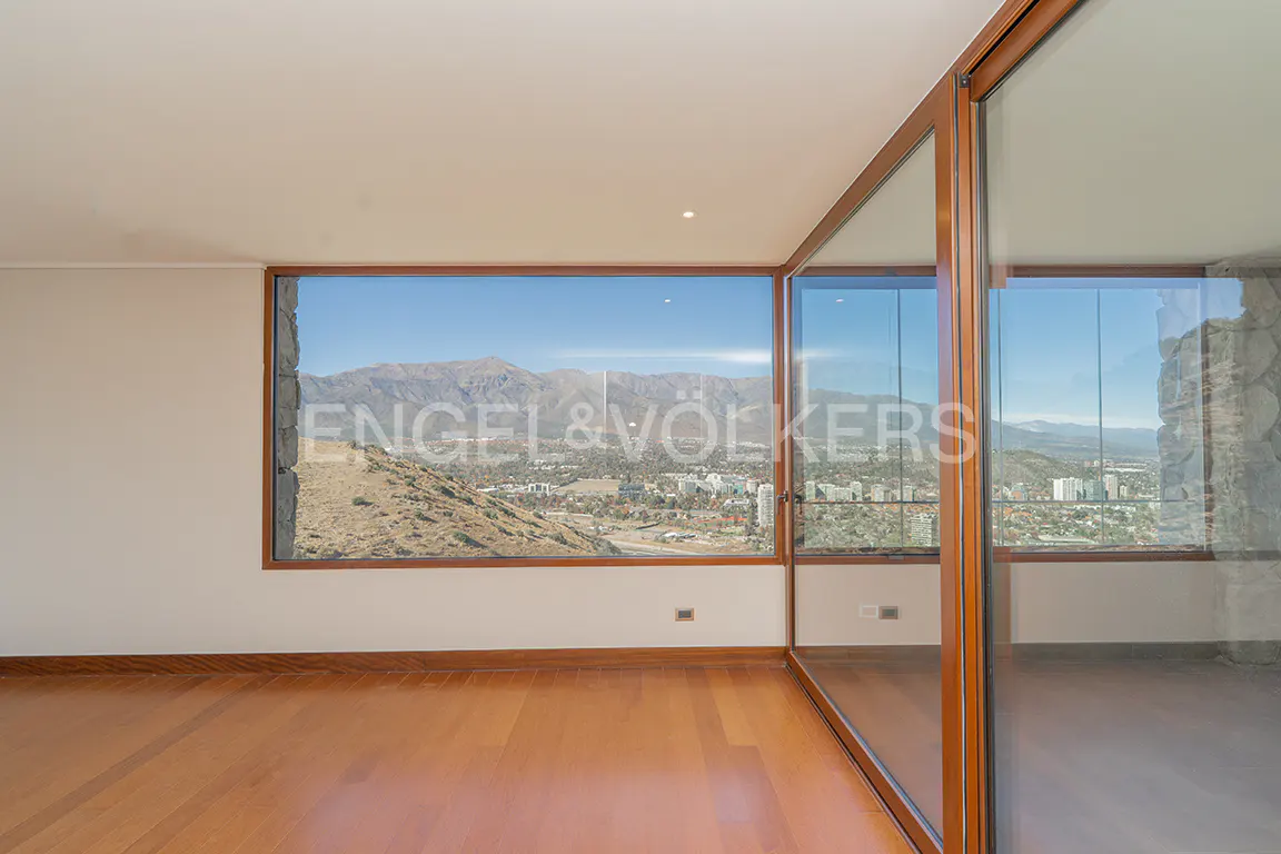 An empty room with wood floors and a large window showing a mountain view.