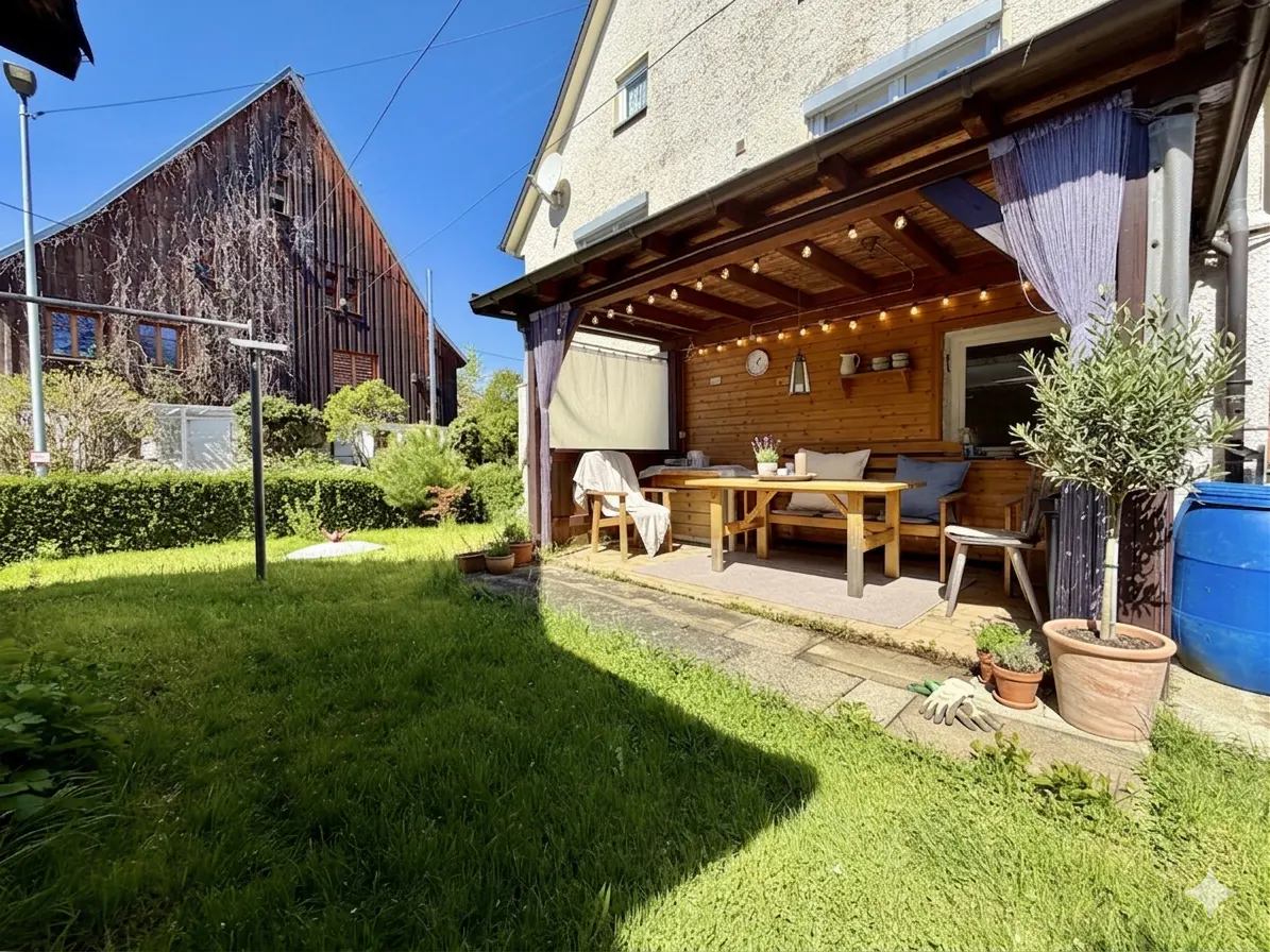 Outdoor patio with wooden table, bench, and chairs. String lights hang from the roof. A green lawn and barn are in the background.