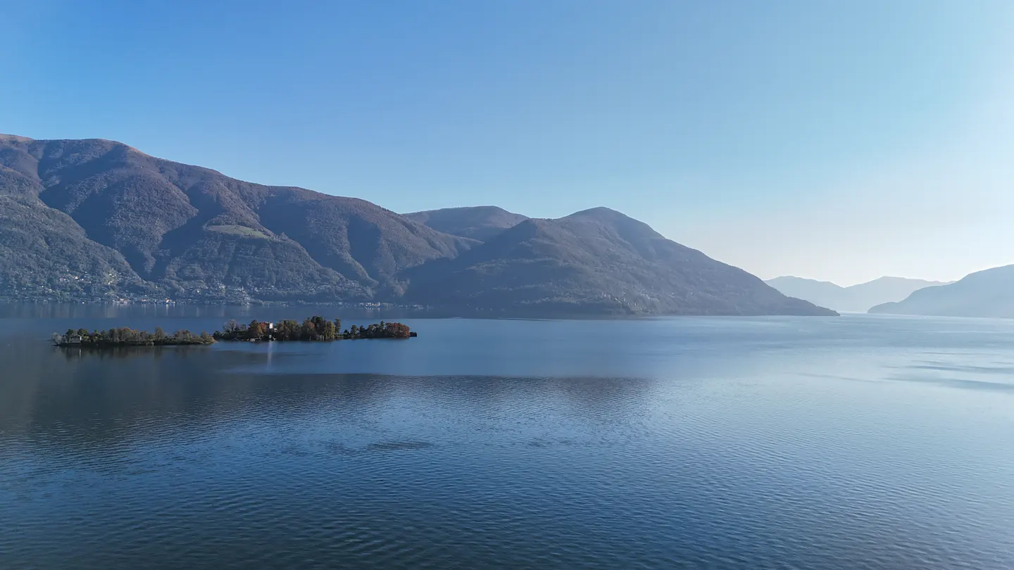 Scenic view of a blue lake with islands and mountains under a clear blue sky.