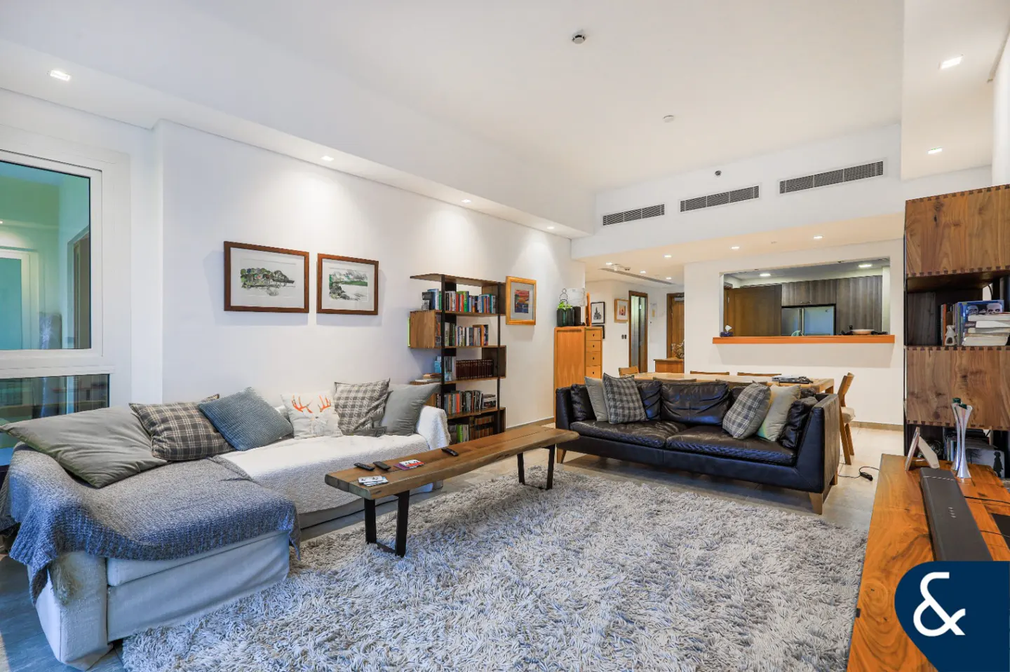 Bright living room with a gray shag rug, a sectional sofa, a black leather sofa, and a wooden coffee table.