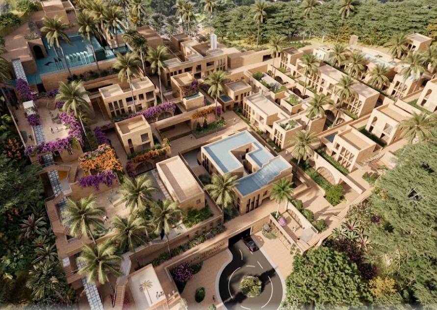 Aerial view of a luxury resort with tan buildings, palm trees, purple flowers, and a circular driveway.