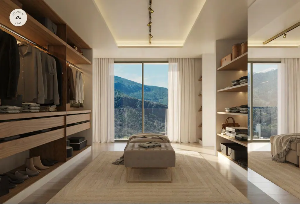 A walk-in closet with wood shelving, clothes, and shoes. A beige ottoman sits on a patterned rug in front of a window with a mountain view.