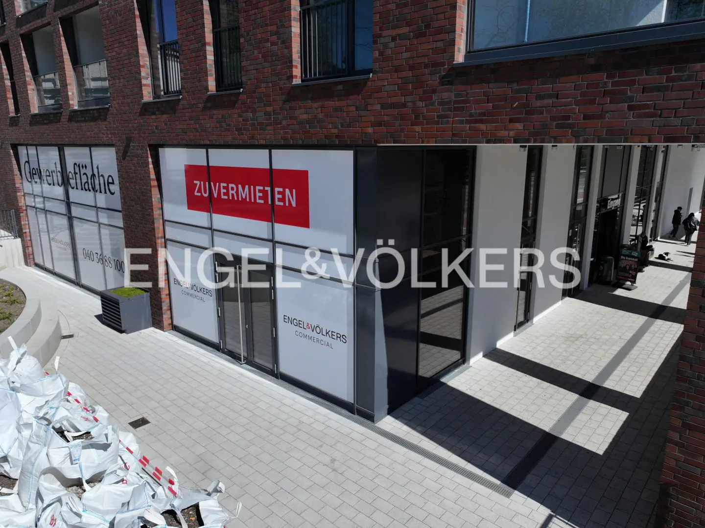 Engel & Völkers Commercial office with "ZU VERMIETEN" (for rent) sign on the window of a brick building.