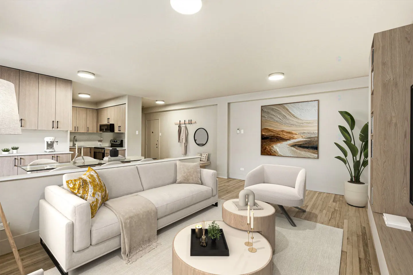 Open-concept living space with a white sofa, round wood tables, and a modern kitchen in the background. Neutral tones and natural light.