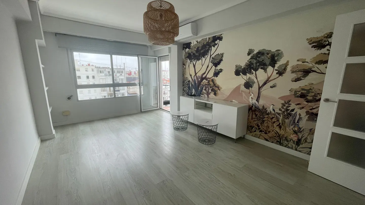 Bright room with light wood floors, a woven pendant light, a white sideboard, and a scenic landscape wallpaper.