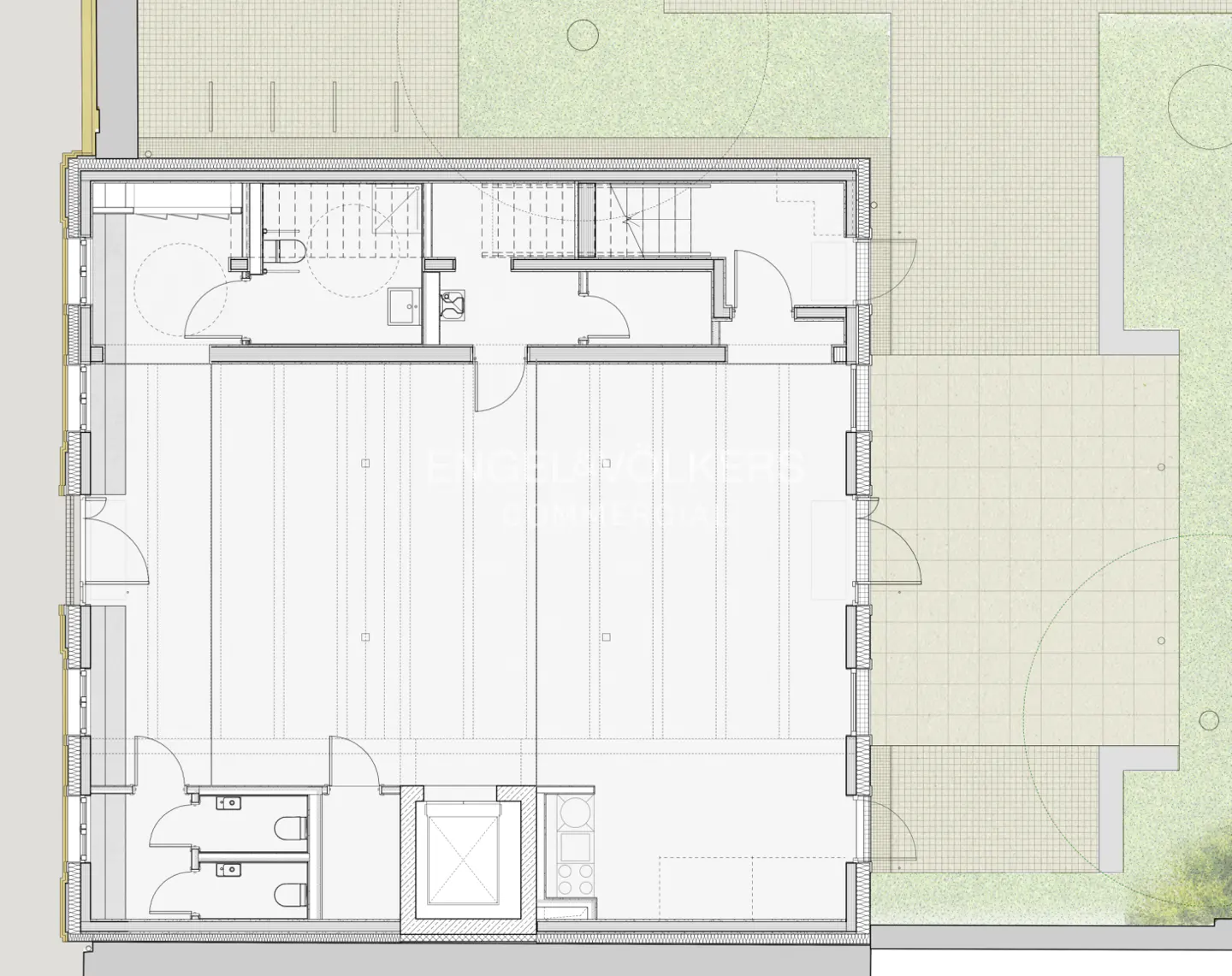 Floor plan of a building with a large open space, bathrooms, stairs, and a kitchen area. Outside, there's a patio and a grassy yard.