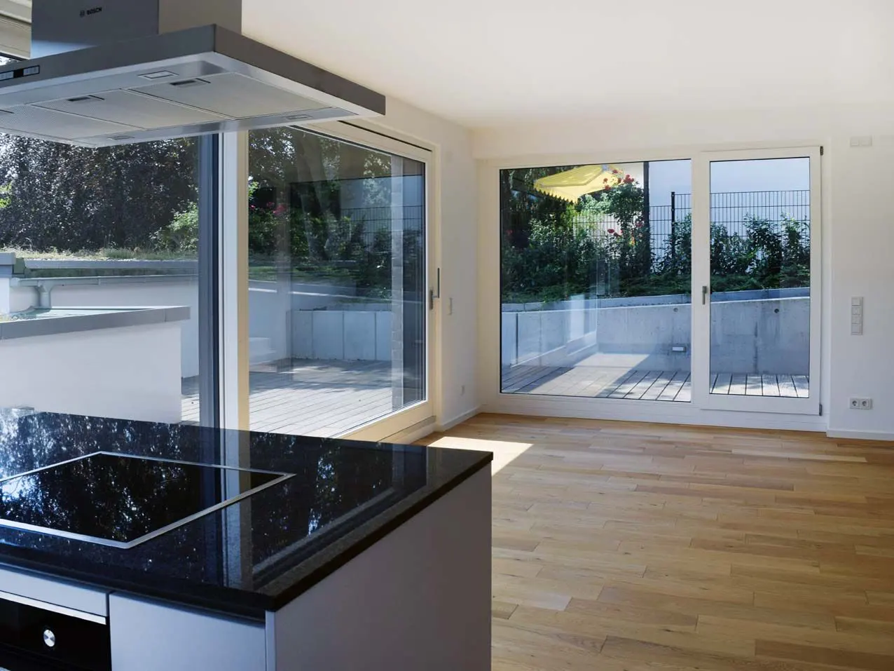 Bright, modern kitchen with wood floors, black granite countertop, and sliding glass doors to a patio.