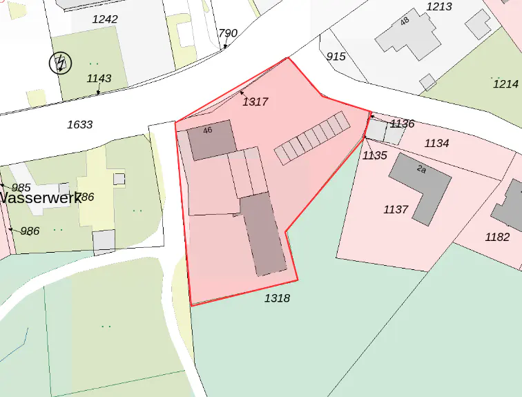 A map view of a property outlined in red, including buildings and parking spaces, surrounded by streets and other properties.