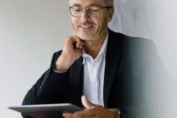 Mann im Anzug mit Brille, der ein Tablet benutzt