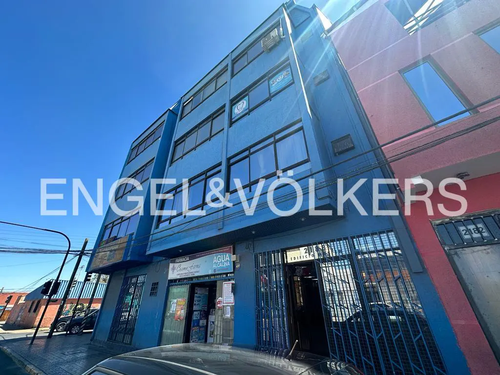 Exterior view of a blue, multi-story commercial building with Engel & Völkers logo, under a clear blue sky.