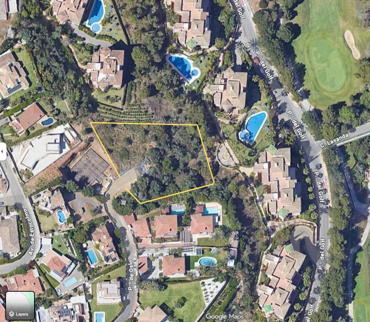 Aerial view of a vacant lot outlined in yellow, surrounded by luxury homes with pools and a golf course.