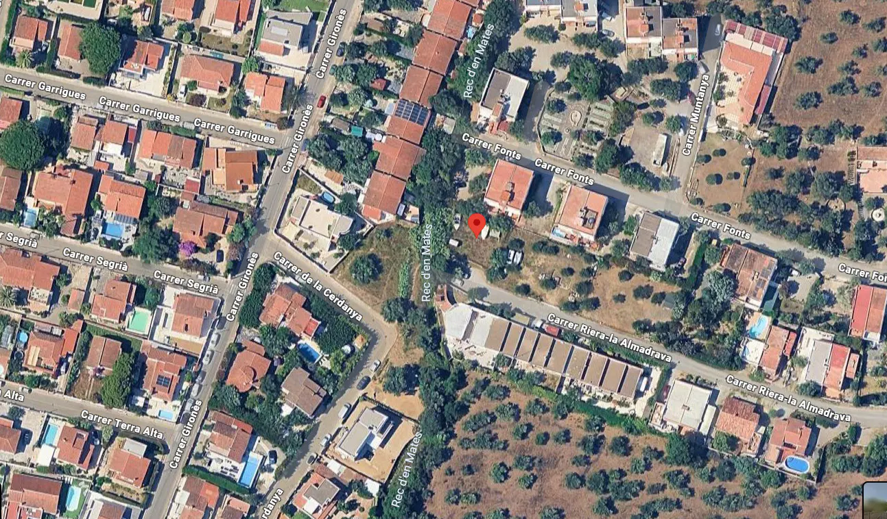 Aerial view of a residential area with houses, streets, and trees, marked with a red pin.